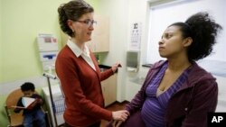 Perawat Danielle Kraessig memeriksa pasiennya, Yakini Branch di sebuah klinik di Berwyn, Illinois, AS (foto: dok). Kaum Ibu kini menjadi pencari nafkah bagi 40 persen keluarga AS. 