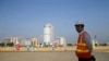 FILE - In this Jan. 2, 2018, photo, a Chinese construction worker stands on land that was reclaimed from the Indian Ocean for the Colombo Port City project, initiated as part of China's ambitious One Belt One Road initiative, in Colombo, Sri Lanka. 