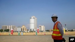 FILE - In this Jan. 2, 2018, photo, a Chinese construction worker stands on land that was reclaimed from the Indian Ocean for the Colombo Port City project, initiated as part of China's ambitious One Belt One Road initiative, in Colombo, Sri Lanka. 