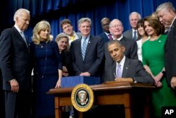 President Barack Obama signs the 21st Century Cures Act in the South Court Auditorium in the Eisenhower Executive Office Building on the White House complex in Washington, Dec. 13, 2016. Standing behind, from left are, Vice President Joe Biden, his wife, Jill Biden, Rep. Frank Pallone, D-N.J., Sen. Lamar Alexander, R-Tenn., House Minority Leader Nancy Pelosi of Calif., and Rep. Fred Upton, R-Mich.