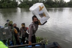 Seorang polisi mengengkat kotak suara dari perahu untuk didistribusikan ke tempat pemungutan suara menjelang pelaksanaan Pilkada di Sidoarjo, Jawa Timur, 8 Desember 2020.