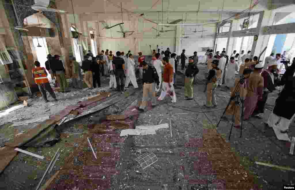 Security officials, rescue workers and members of the media gather at the site of a suicide bomb attack in a Shi&#39;ite Muslim mosque in Peshawar, Pakistan, June 21, 2013. 