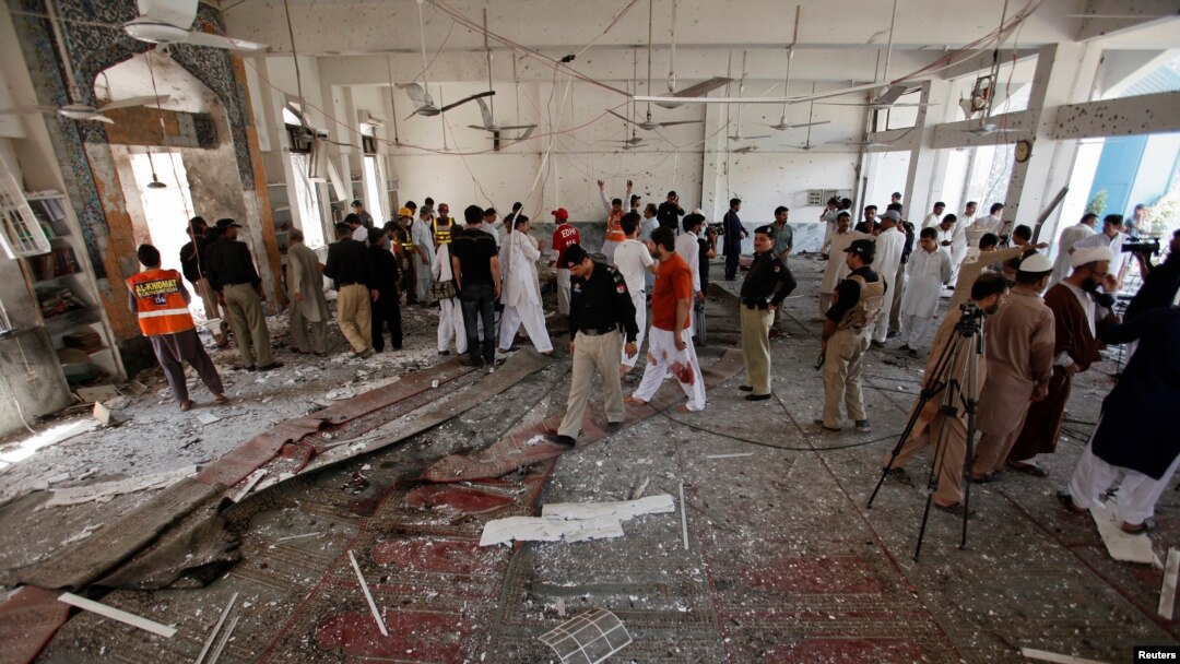 Security officials, rescue workers and members of the media gather at the site of a suicide bomb attack in Shi'ite Muslim mosque in Peshawar, Pakistan, June 21, 2013. 