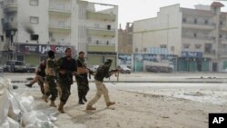 Des soldats libyens courent pour se mettre à couvert durant des affrontements contre les miliciens extremistes à Benghazi, Libye, le 30 octobre 2014.