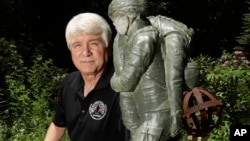 In a photo from June 9, 2017, former Army medic James McCloughan kneels next to a statue presented to him by a fellow soldier in South Haven, Michigan. McCloughan saved the lives of 10 soldiers during the Battle of Nui Yon Hill in May 1969 in Vietnam.