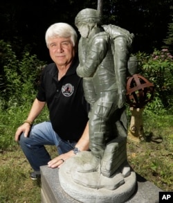In a photo from June 9, 2017, former Army medic James McCloughan kneels next to a statue presented to him by a fellow soldier in South Haven, Michigan. McCloughan saved the lives of 10 soldiers during the Battle of Nui Yon Hill in May 1969 in Vietnam.