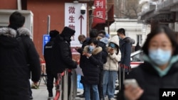 People scan a QR code to display their health code as they line up outside a hospital to get COVID-19 tests in Beijing on Jan. 14, 2021.