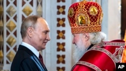 Russian Orthodox Church Patriarch Kirill, right, greets Russian President Vladimir Putin after conducting an Orthodox Easter service at the Cathedral of Christ the Saviour in Moscow, Russia, May 5, 2024.