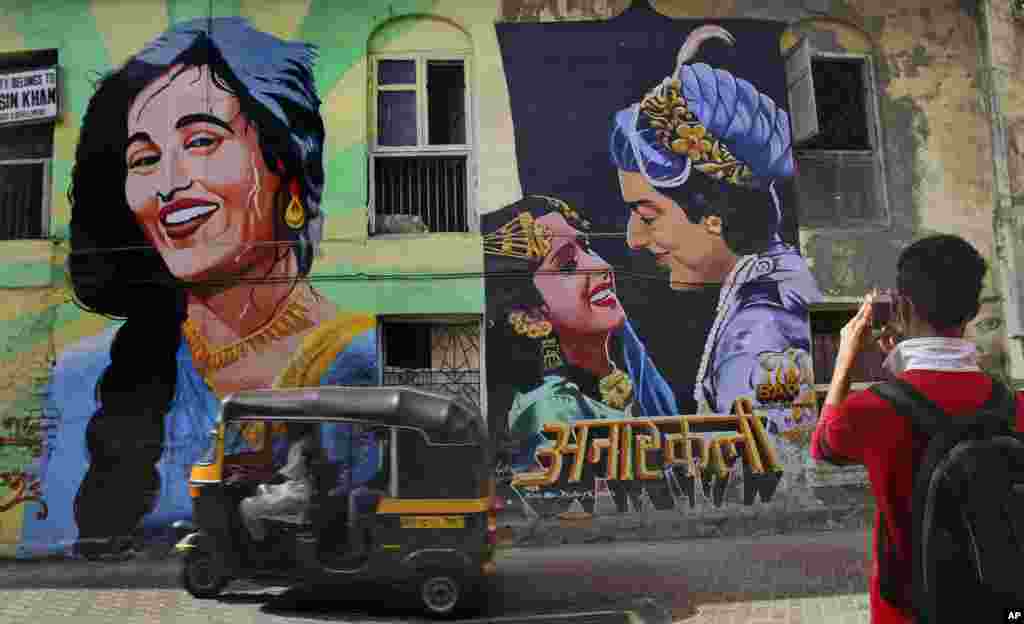 Seorang pemuda memotret mural film India "Anarkali" di Mumbai. India baru saja memperingati 100 tahun industri Bollywood yang ditandai dengan pemutaran film bisu "Raja Harischandra" pada 3 Mei 1913. (AP/Rafiq Maqbool)