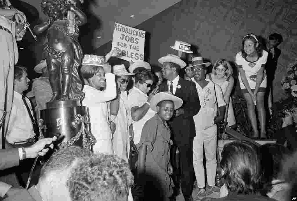 FILE - The Rev. Ralph Abernathy, center in dark suit, wears a Rockefeller campaign button on his lapel as he is greeted in the lobby of the Fontainebleau Hotel, headquarters of the Republican National Convention, Miami Beach, Fla., Aug. 6, 1968.