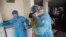 Nurses wearing protective gear walk with an elderly woman at the Mas Vida home for senior citizens in Lima, Peru, May 12, 2020. 