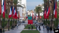 People walk past Moroccan and French flags on Mohammed V avenue ahead of French president Emmanuel Macron official visit to Morocco, in the capital Rabat, Oct. 28, 2024. 