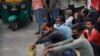 Migrant laborers Nirbhay Yadav, 50, wearing checked scarf, and his son Lovelesh Yadav, left, wait to get employed for the day in New Delhi, India, March 18, 2021.