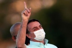 Brazil's President Jair Bolsonaro, who is infected with COVID-19, wears a protective face mask as he attends a Brazilian flag retreat ceremony outside his official residence the Alvorada Palace, in Brasilia, Brazil, Wednesday, July 22, 2020…