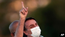 Presiden Brasil Jair Bolsonaro, yang terinfeksi Covid-19, memakai masker pelindung wajah saat menghadiri upacara di Istana Alvorada, di Brasilia, Brasil, Rabu, 22 Juli 2020. (Foto: AP)