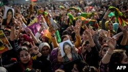 Kurds celebrating success by Kurdish and peshmerga fighters in driving Islamic State militants out of Kobani, hold a photo of a fighter killed in the conflict, near Turkish-Syrian border at Suruc, Sanliurfa province, Jan. 27, 2015.