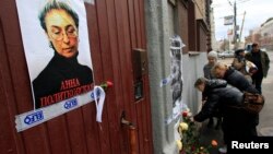 FILE - People lay flowers next to a portrait of slain journalist Anna Politkovskaya near the apartment building where she lived in central Moscow October 7, 2012.