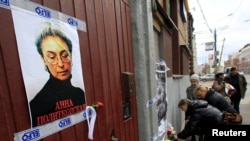 FILE - People lay flowers next to a portrait of slain journalist Anna Politkovskaya near the apartment building where she lived in central Moscow October 7, 2012.