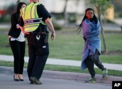20일 수하물 폭발사건이 발생한 텍사스주 오스틴시 근처 셰르츠의 페덱스 배송센터를 빠져나온 여성 직원이 담요를 둘러싼 채 수사 당국 요원을 향해 걸어가고 있다.
