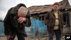 FILE - Valentina Fedoryak and her husband stand outside their home damaged by shelling in Donetsk, Eastern Ukraine, Nov. 12, 2014.