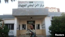 FILE - An armed security guard stands in front of a police station in Benghazi.