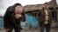 FILE - Valentina Fedoryak and her husband stand outside their home damaged by shelling in Donetsk, Eastern Ukraine, Nov. 12, 2014.