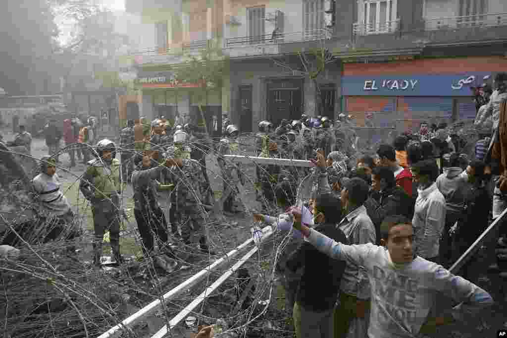 Egyptian protesters stand behind a barbed wire barricade in Tahrir Square in Cairo, November 24, 2011. (AP)