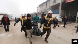 Emergency services carry a body of a person killed in a government airstrike in the city of Idlib, Syria, Feb. 11, 2020. 