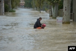 A firefighter helps a youngster to evacuate in a flooded street during a rescue operation following heavy rains that saw rivers bursting banks on Oct. 15, 2018 in Trebes, near Carcassone, southern France.