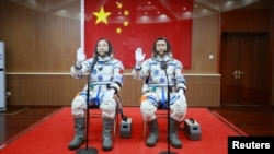 Chinese astronauts Jing Haipeng (L) and Chen Dong wave in front of a Chinese national flag before the launch of Shenzhou-11 manned spacecraft, in Jiuquan, China, October 17, 2016. REUTERS/Stringer 