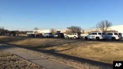 In this photo provided by KWCH-TV, police vehicles line the road after reports of a shooting at an industrial site in Hesston, Kan., Feb. 25, 2016. 