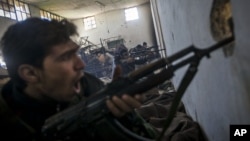 In this Saturday, Dec. 15, 2012 photo, Free Syrian Army fighters aim their weapons as they chant religious slogans during heavy clashes with government forces at a military academy besieged by the rebels north of Aleppo, Syria. 