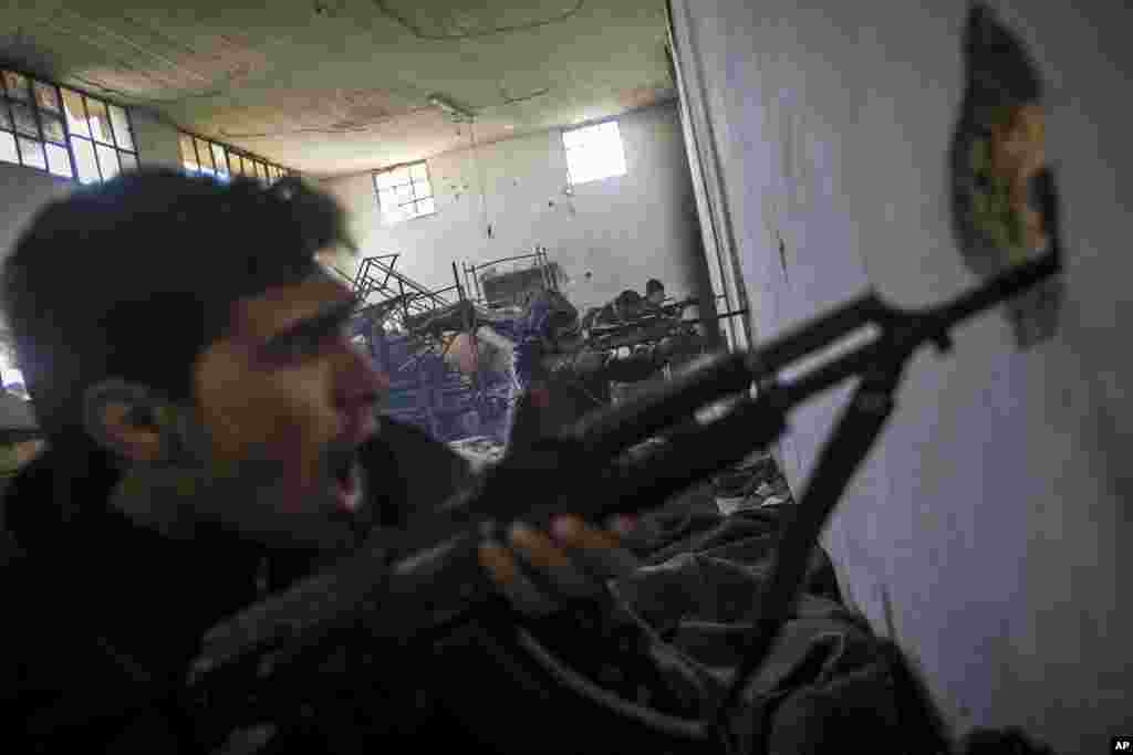 In this Saturday, Dec. 15, 2012 photo, Free Syrian Army fighters aim their weapons as they chant religious slogans during heavy clashes with government forces at a military academy besieged by the rebels north of Aleppo, Syria.