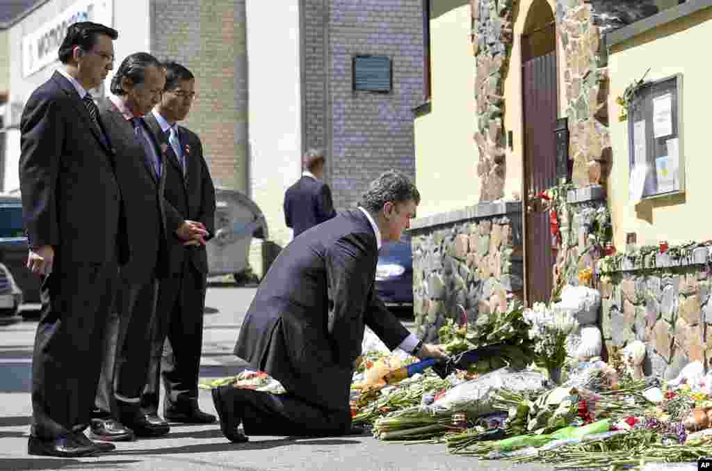 Malaysian diplomats stand as Ukrainian President Petro Porosheko expresses his condolences outside the Malaysian Embassy in Kyiv, July 21, 2014.