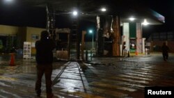 A plainclothes Mexican police officer takes pictures with his cellphone of a gas station following an arson attack in Morelia, Oct. 27, 2013. 