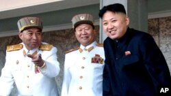 El líder norcoreano, Kim Jong Un, sonríe mientras conversa con dos miliates de la Comisión Militar Central de ese país.