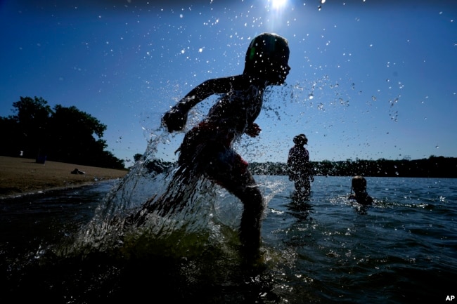 FILE - Judah Boyle, of Des Moines, Iowa, splashes water as he runs on the beach at Gray's Lake Park, Monday, Aug. 26, 2024, in Des Moines, Iowa. (AP Photo/Charlie Neibergall)