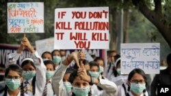 FILE - Schoolchildren hold banners to express their distress at the alarming levels of pollution in the city, in New Delhi, India, Nov. 15, 2017.
