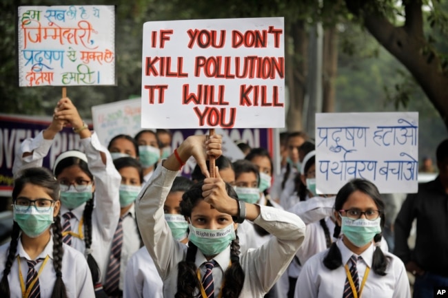 FILE - Schoolchildren hold banners to express their distress at the alarming levels of pollution in the city, in New Delhi, India, Nov. 15, 2017.