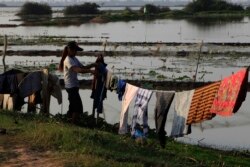 In this March 24, 2018, photo, a Cambodian girl dries clothes at Boeung Thom lake on the outskirts of Phnom Penh, Cambodia. (AP Photo/Heng Sinith)