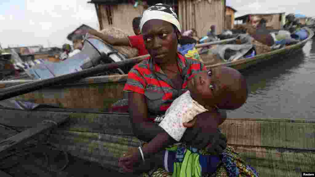 A woman sits in a canoe with her child as the government begins the demolition of homes in Legas.