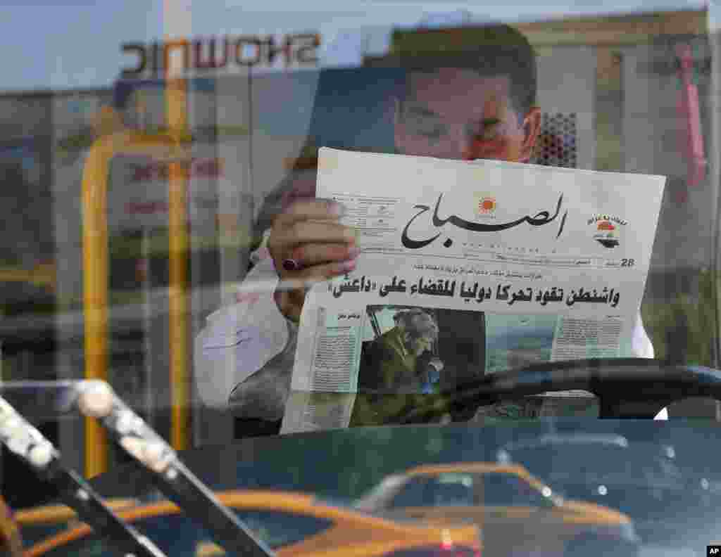 An Iraqi man reads a newspaper with front page headlines reporting U.S. President Barack Obama&#39;s plan to battle Islamic State militants, with an accompanying photo of Secretary of State John Kerry&#39;s visit, in Baghdad, Sept. 11, 2014.