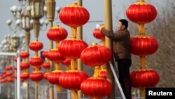 A man hangs lanterns along a street ahead of the Chinese Lunar New Year in Xuchang, Henan province, China, January 15, 2017. 