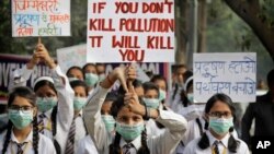 FILE - Schoolchildren hold banners to express their distress at the alarming levels of pollution in the city, in New Delhi, India, Nov. 15, 2017.