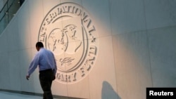 FILE — A man walks past the International Monetary Fund (IMF) logo at its headquarters in Washington, U.S., May 10, 2018. 