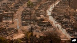 Two people ride bicycles amid the destruction left behind by the Palisades Fire in the Pacific Palisades neighborhood of Los Angeles, Jan. 9, 2025. 