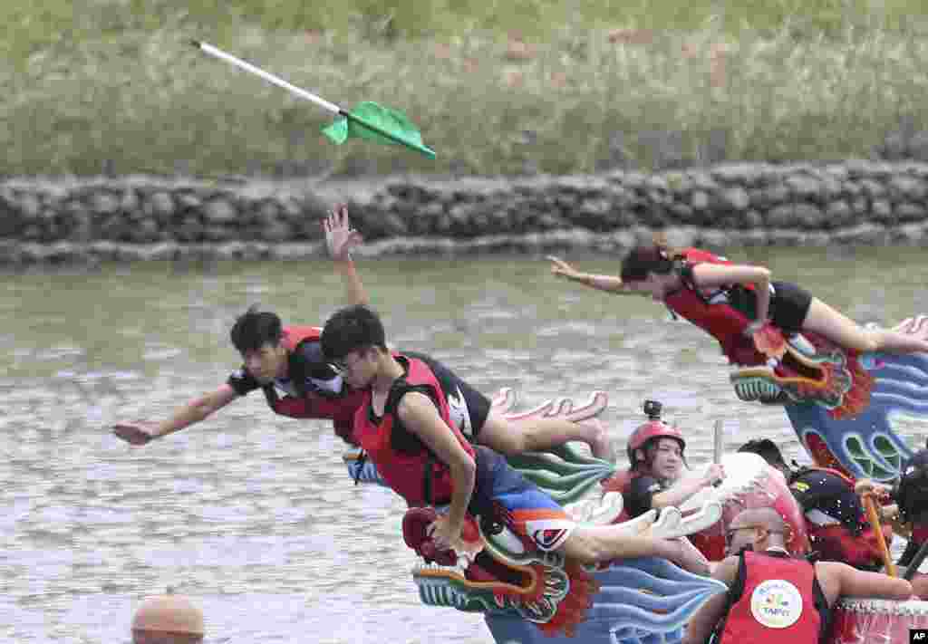 A boat leader reaches out to grab a finish line flag during the traditional Chinese dragon boat race in Taipei, Taiwan.