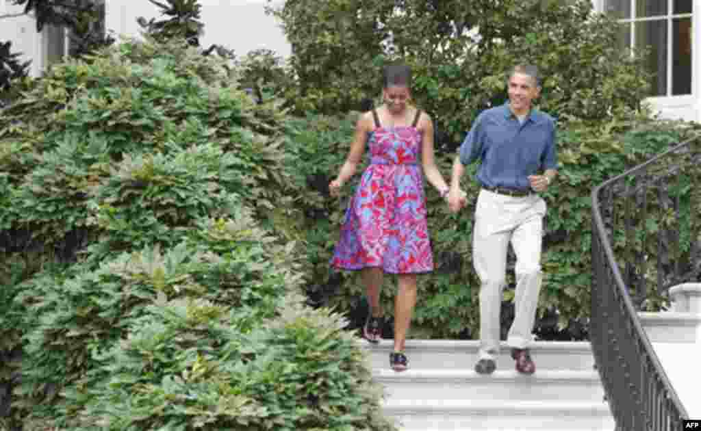 President Barack Obama and first lady Michelle Obama walk down the South Portico staircase to welcome military families to an Independence Day celebration on the South Lawn of the White House in Washington, Monday, July 4, 2011. (AP Photo/Charles Dharapak