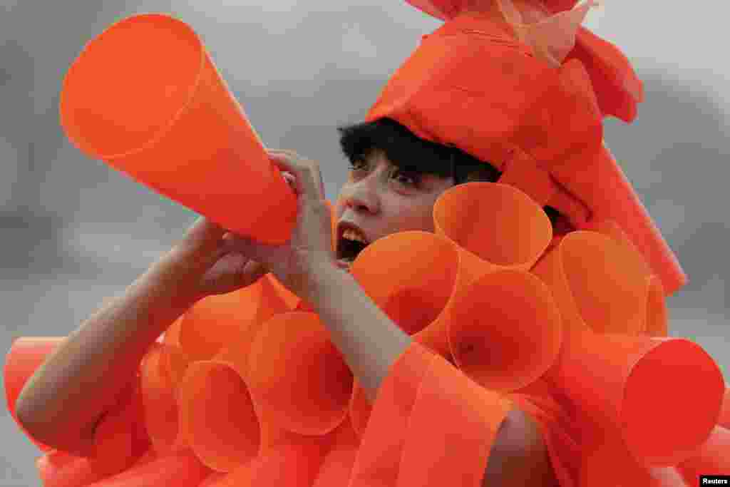 Chinese artist Kong Ning in her costume made of hundreds of orange plastic blowing horns during her art performance raising awareness of the hazardous smog in a historical part of Beijing, China.