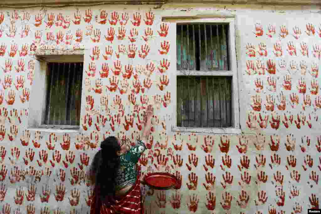 Meenaben Soni makes a red handprint on the wall on the first day of Navratri during which devotees worship the Hindu goddess Durga, at the old city of Ahmedabad, India.